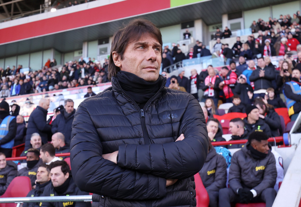 Antonio Conte stares into the middle distance with his arms crossed, a concerned expression on his face.