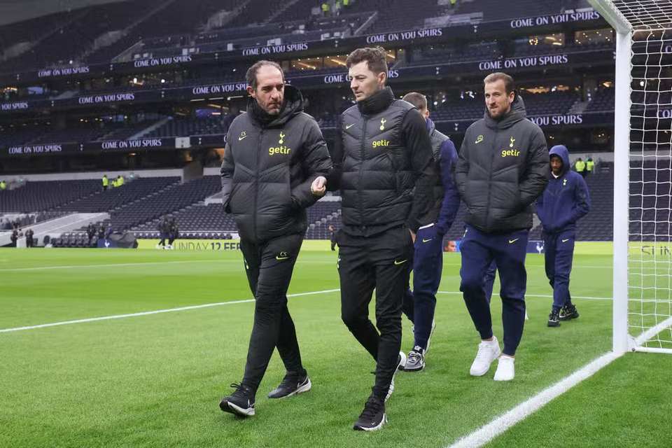 Christian Stellini and Ryan Mason walk side by side on the pitch at Tottenham Hotspur Stadium.