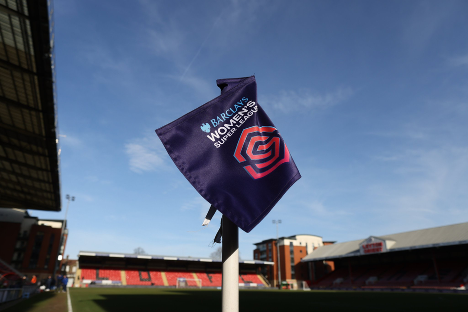 A corner flag for a Barclays Women's Super League match is in the foreground of a background shot of Brisbane Road.
