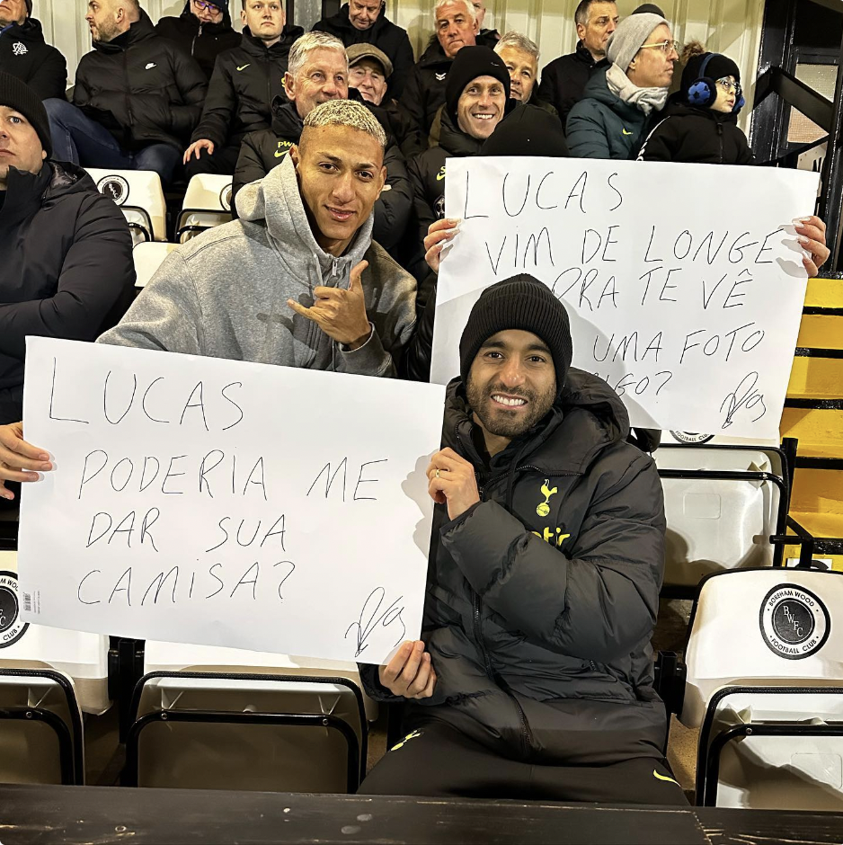 Richarlison holds up a sign next to Lucas Moura that says (in Portuguese) "Lucas can I have your shirt?" 