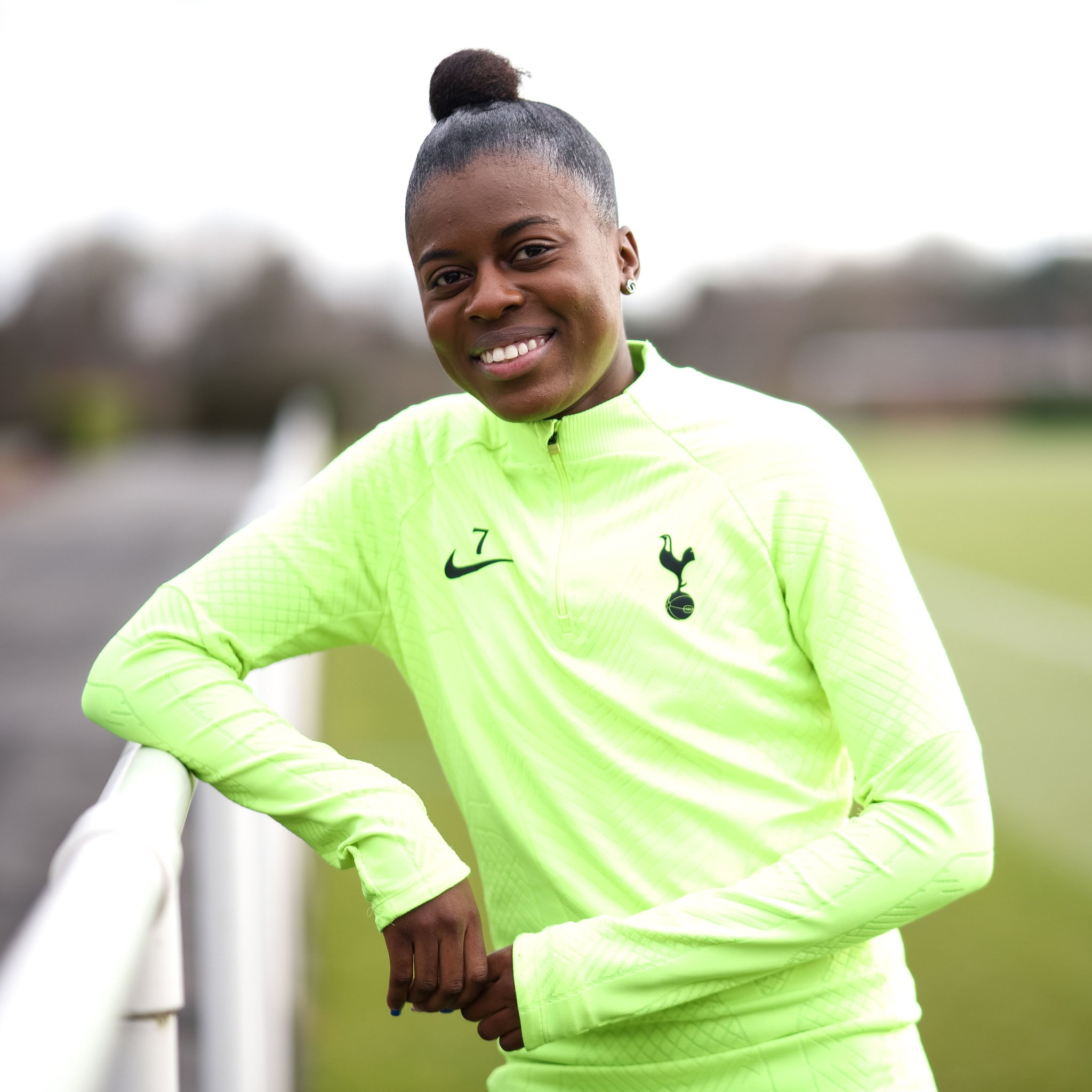 Jessica Naz leans against a fence at the training ground and smiles.