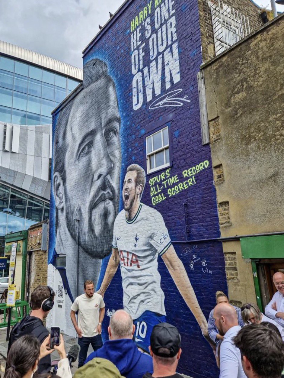 Harry Kane standing in front of the new mural depicting his face and one of his goal celebrations.