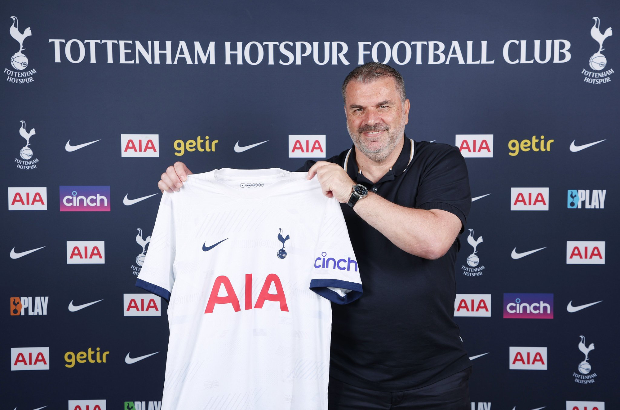 Ange Postecoglou holds up a Tottenham home shirt.