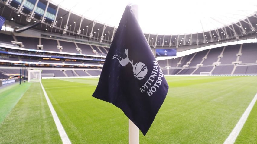 A Tottenham Hotspur crest corner flag in the foreground of the Tottenham Hotspur stadium.