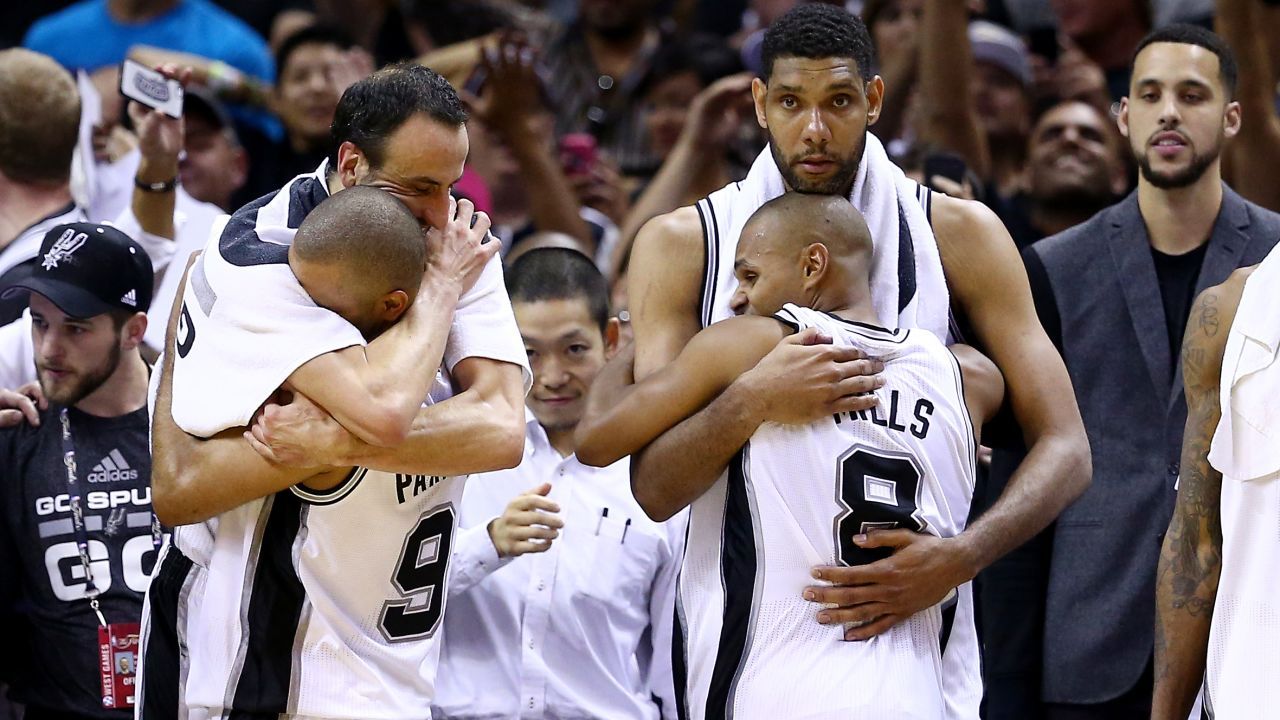 Manu Ginobili hugs Tony Parker while Tim Duncan hugs Patty Mills.