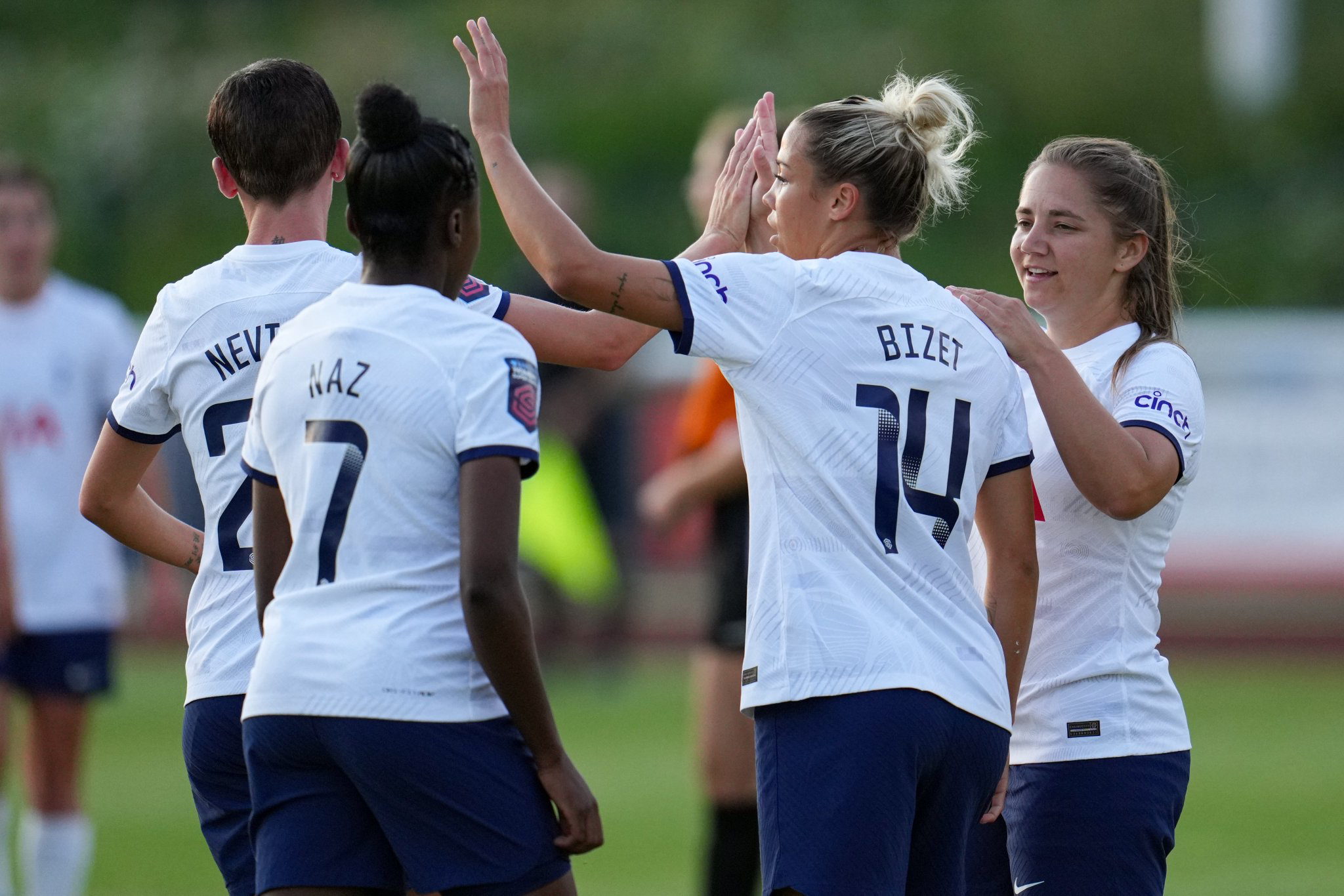 Several Spurs Women players high five after scoring a goal.