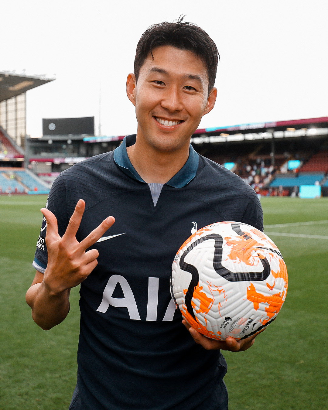 Son Heung-min holds up three fingers and the match ball to celebrate his hat trick.