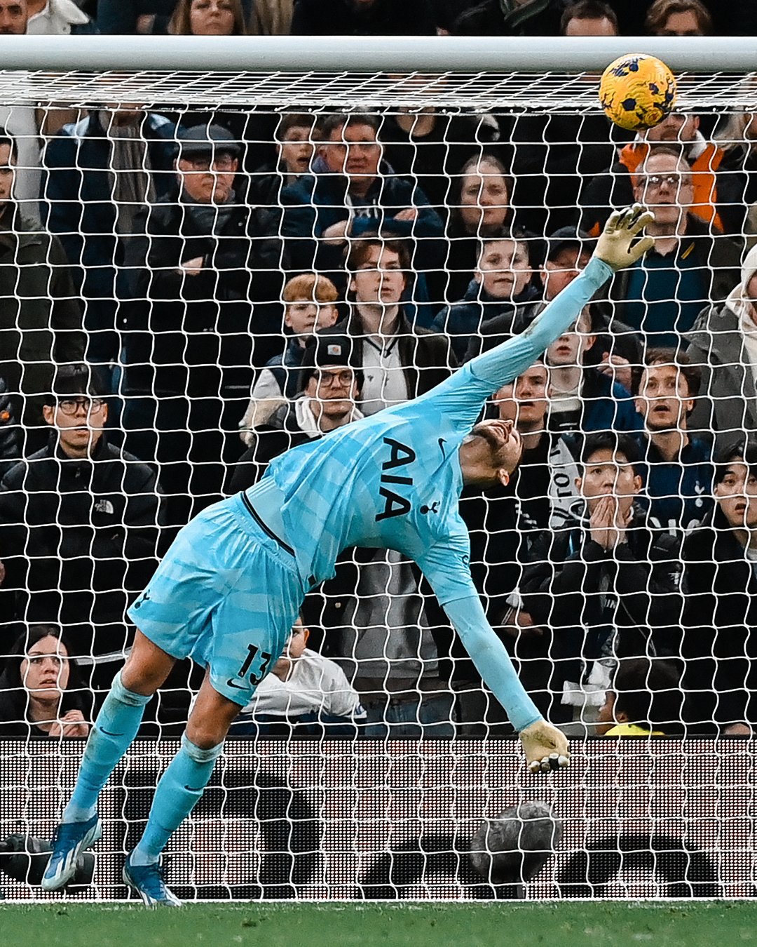 Guglielmo Vicario makes a fingertips save at full extension on Arnaut Danjuma's shot.