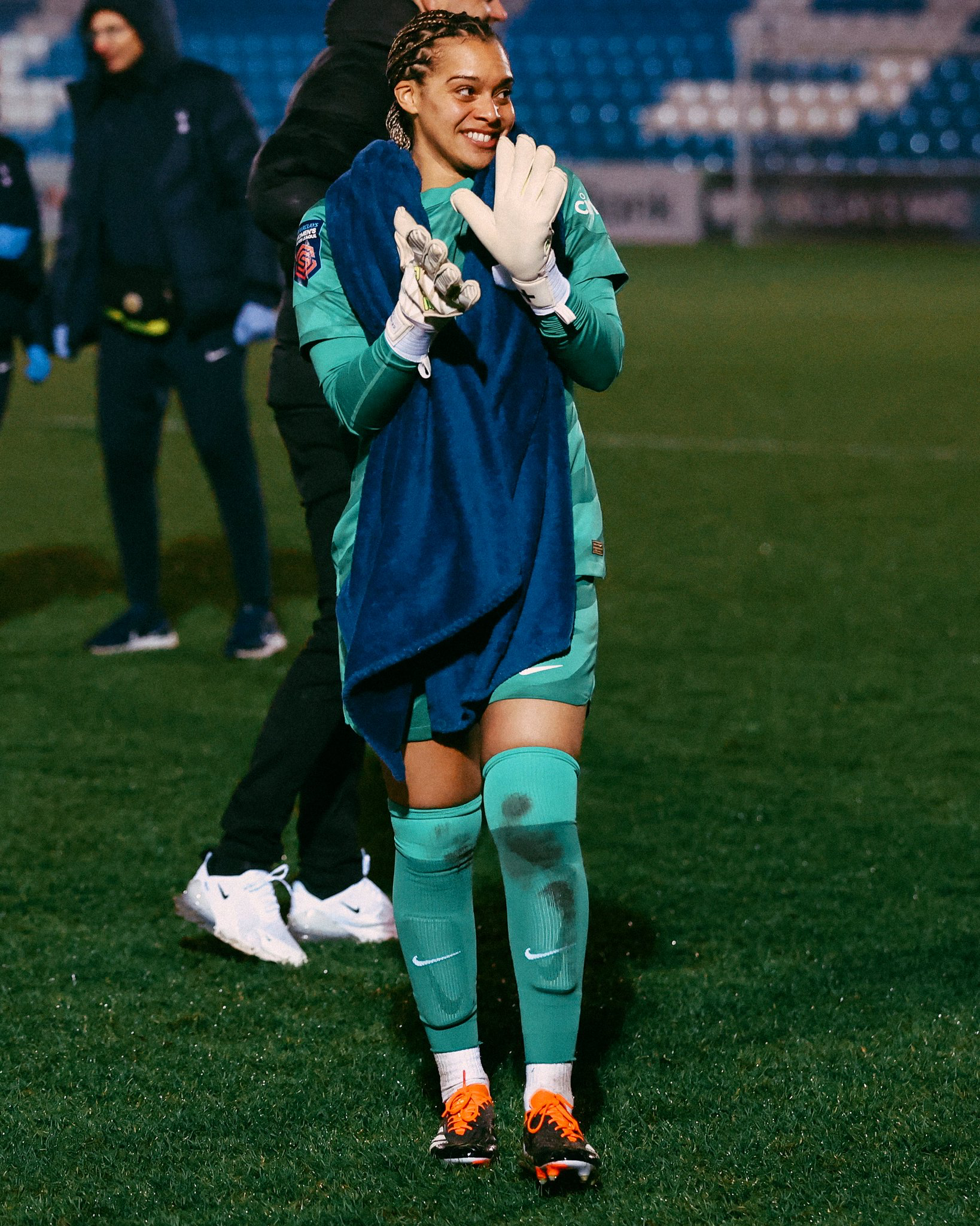 Becky Spencer claps with a towel around her shoulders after the final whistle.