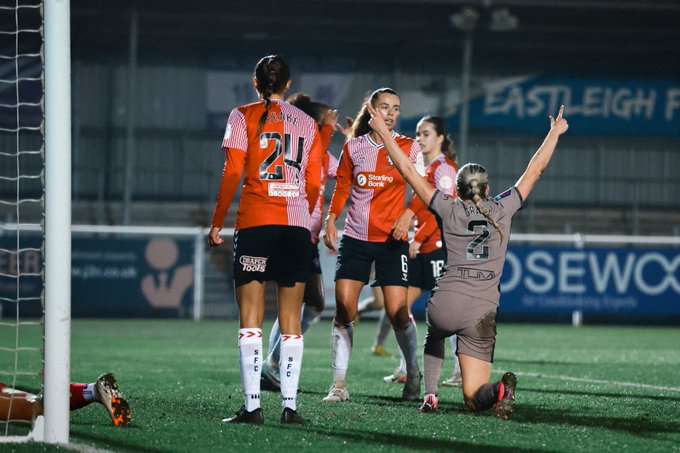 Charli Grant kneels with her arms up to celebrate her first Spurs goal.