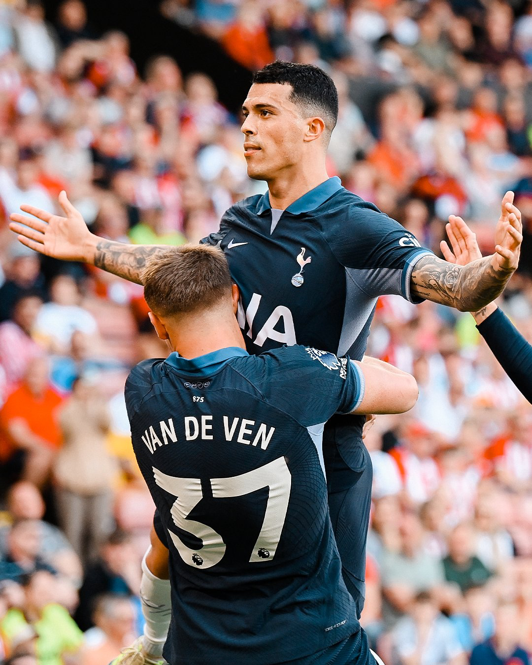 Pedro Porro is lifted into the air by Micky van de Ven and extends his arms.