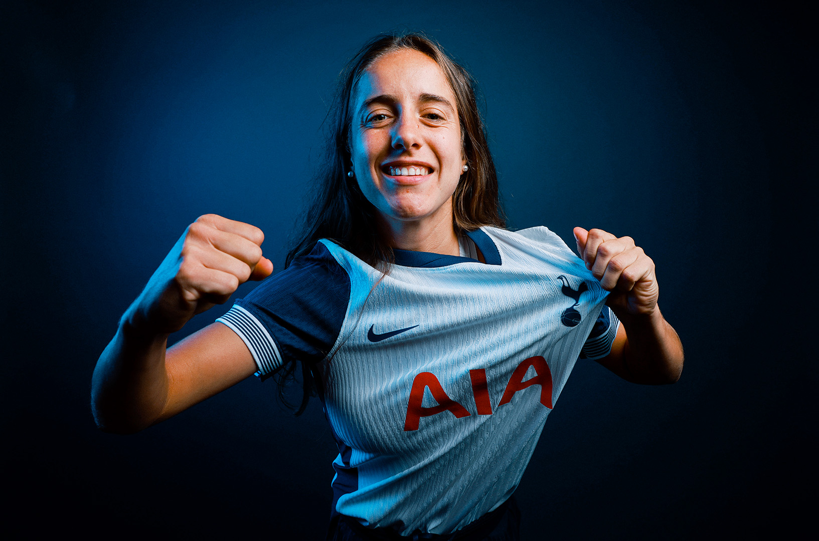 Maite Oroz holds up the Tottenham badge on her shirt and brandishes a fist. 