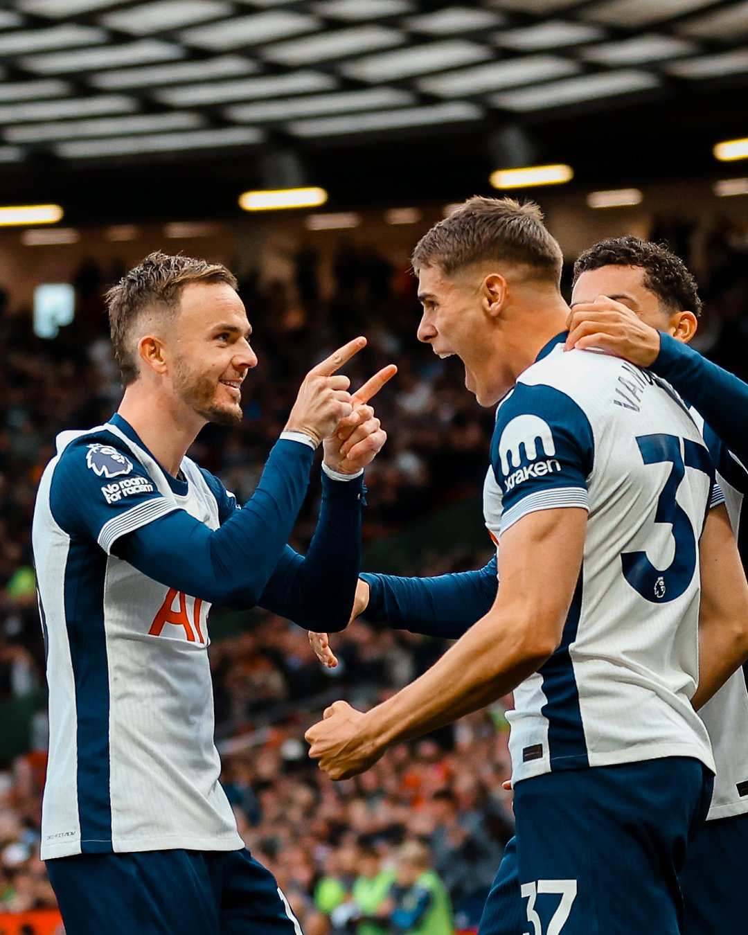 James Maddison points both fingers at Micky van de Ven and smiles.