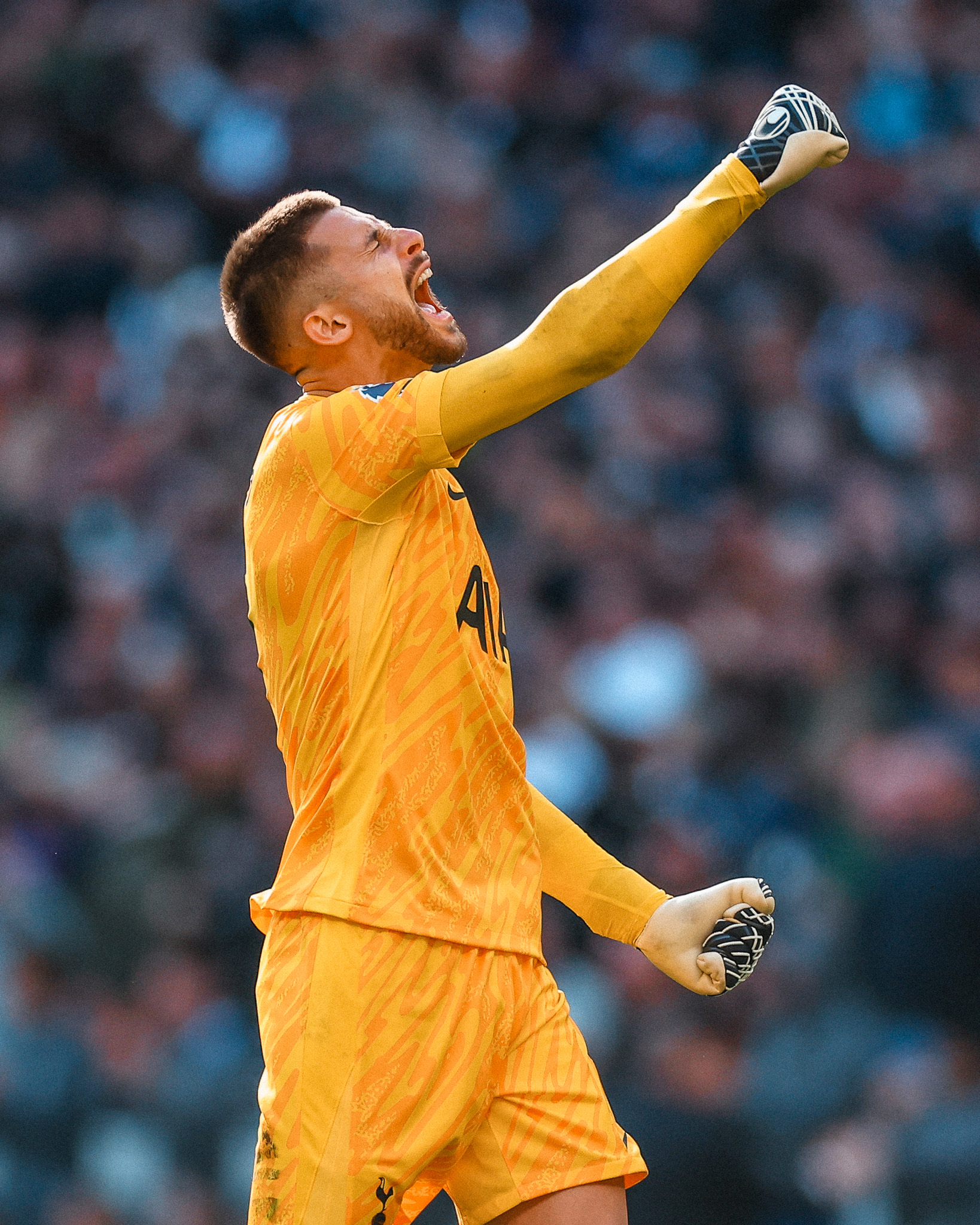 Guglielmo Vicario raises his fist in celebration in his yellow keeper kit.