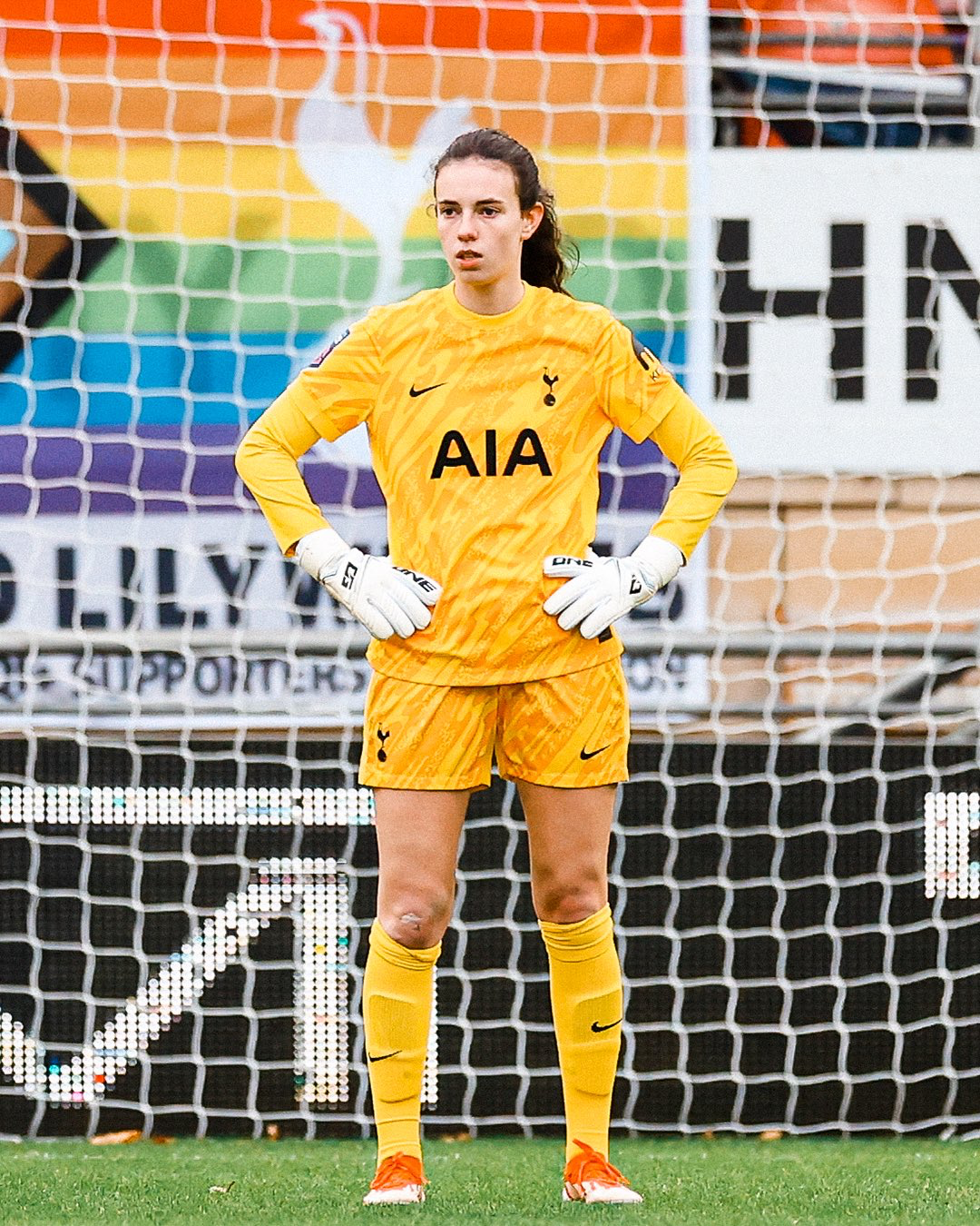 Eleanor Heeps stands with her hands on her hips in her yellow keeper kit on her senior debut.