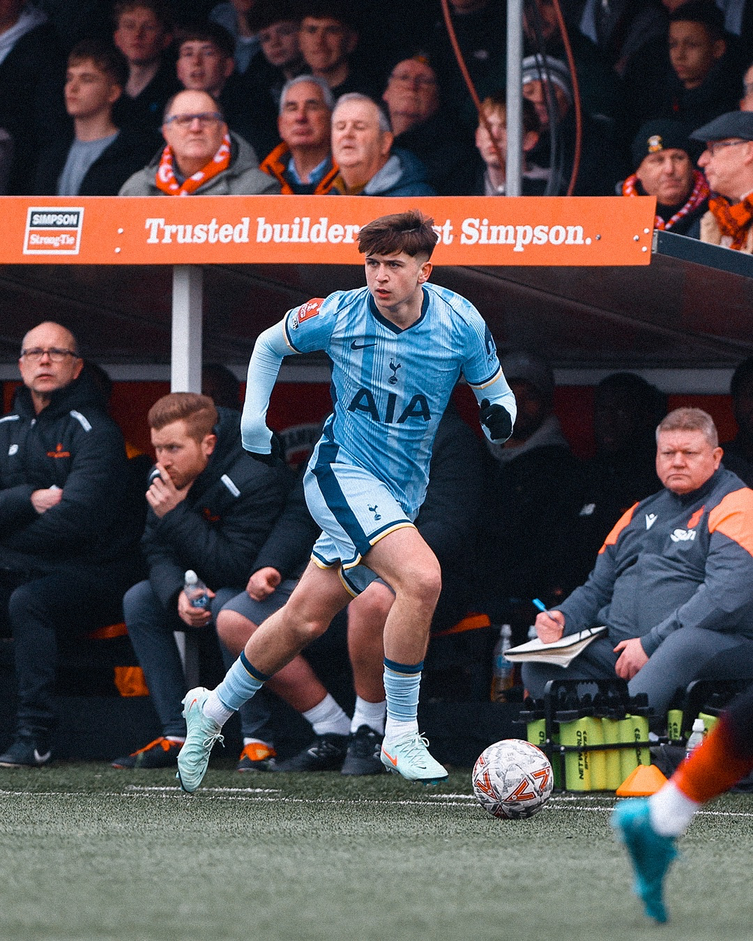 Mikey Moore dribbles the ball near Tamworth's bench. 