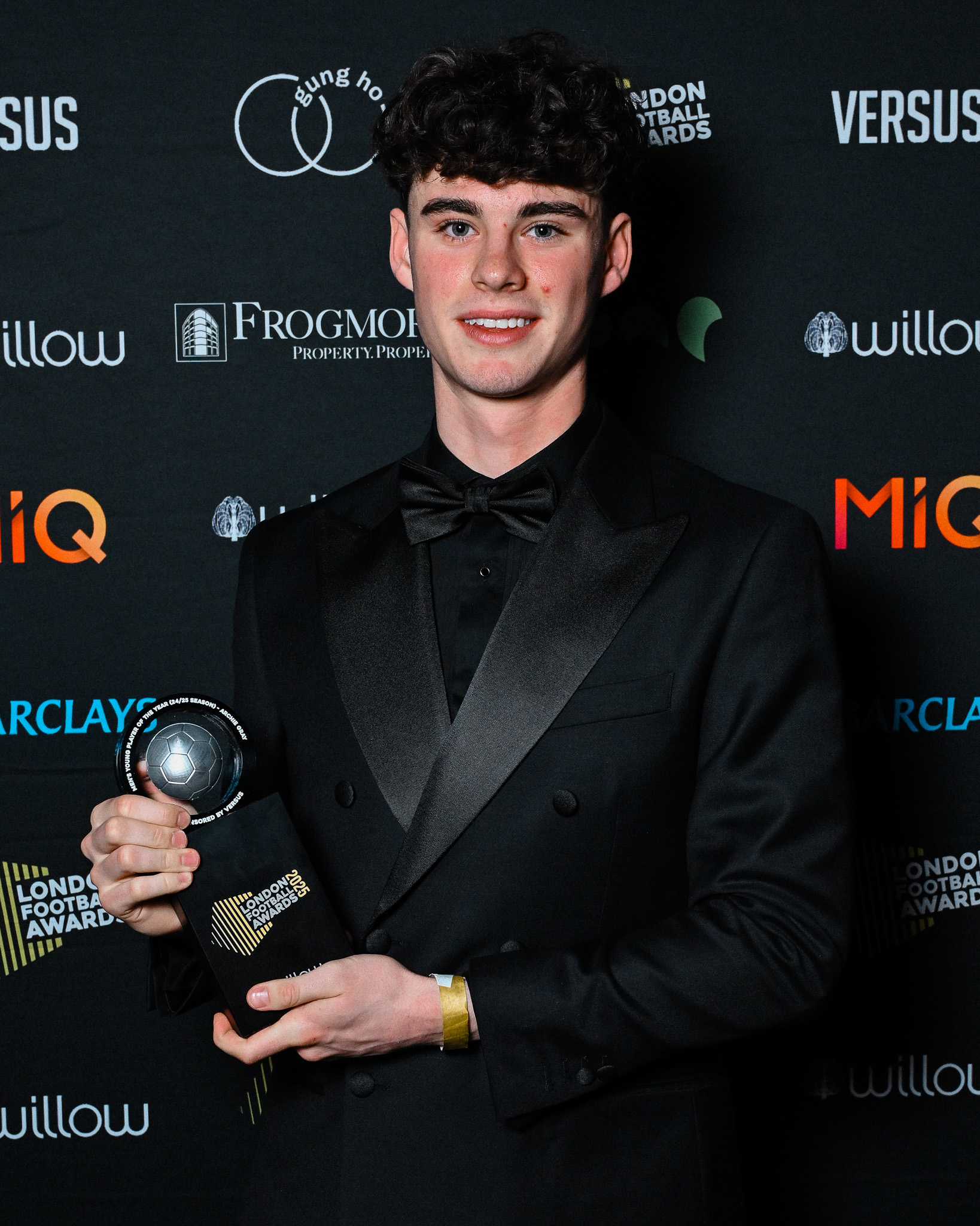 Archie Gray wears a monochrome black suit and holds up his award for Men's Young Player of the Year at the London Football Awards.