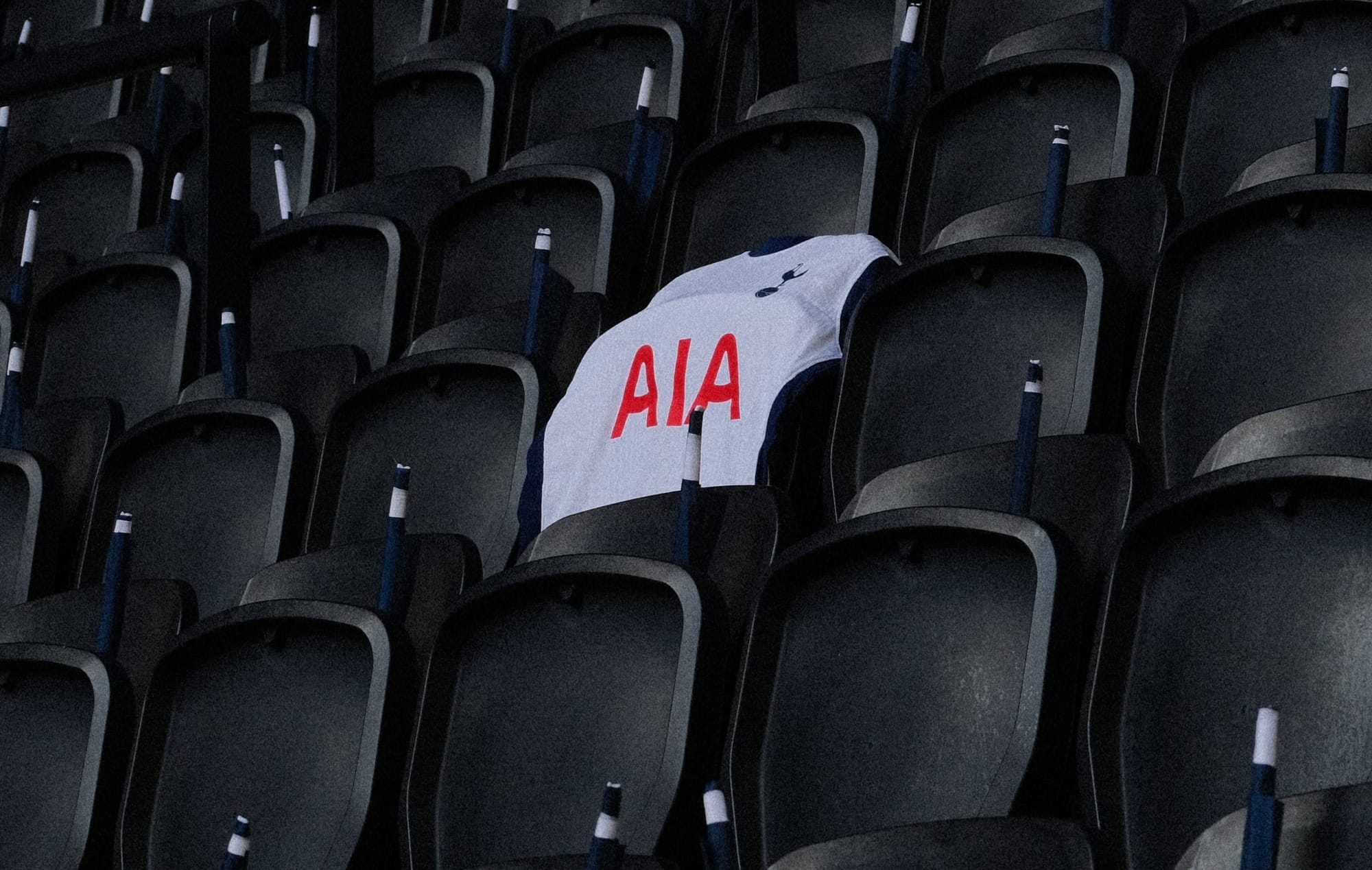 A white Spurs home kit is draped over an empty seat in the stadium.