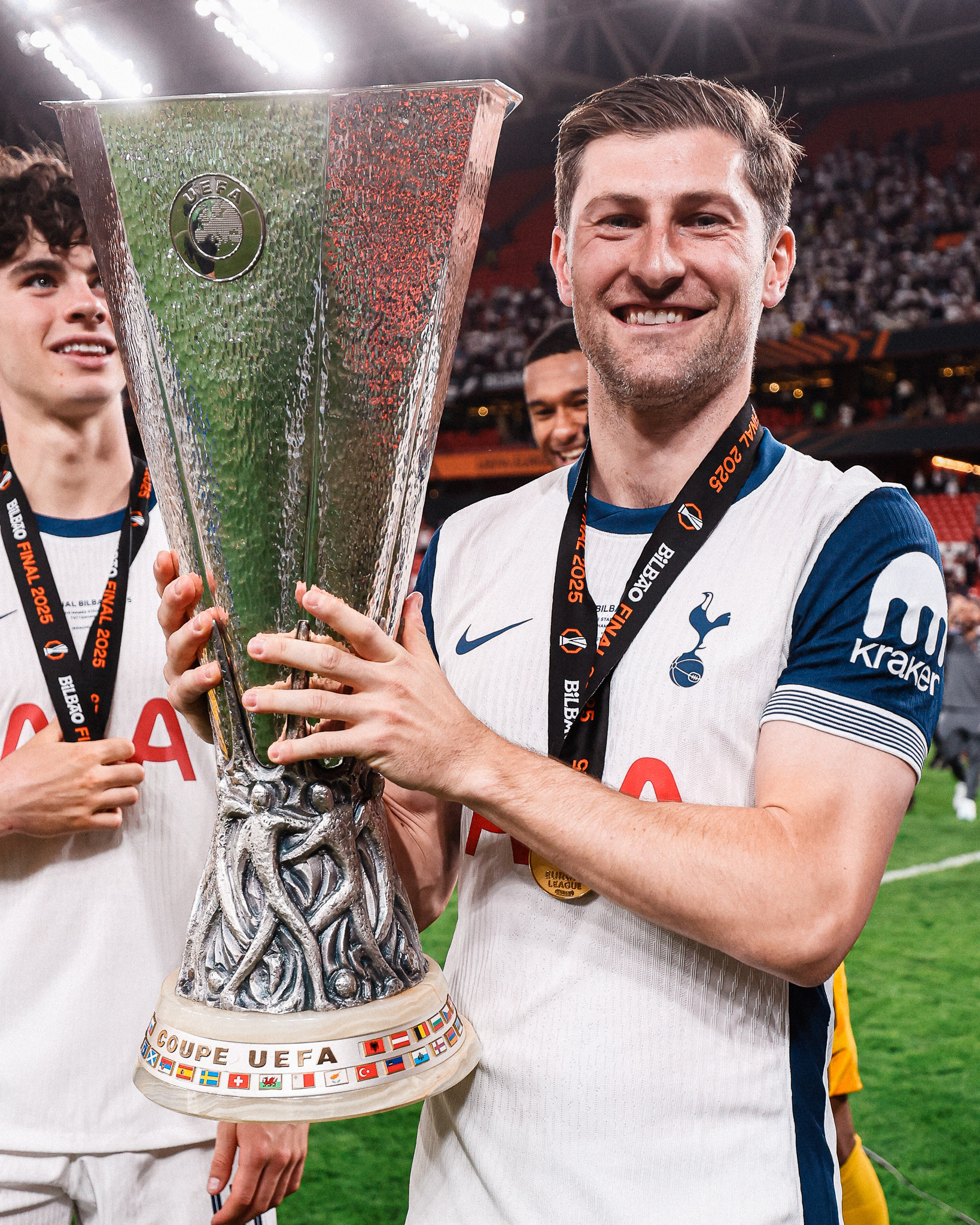 Ben Davies holds up the Europa League trophy after the final, with Archie Gray in the background.
