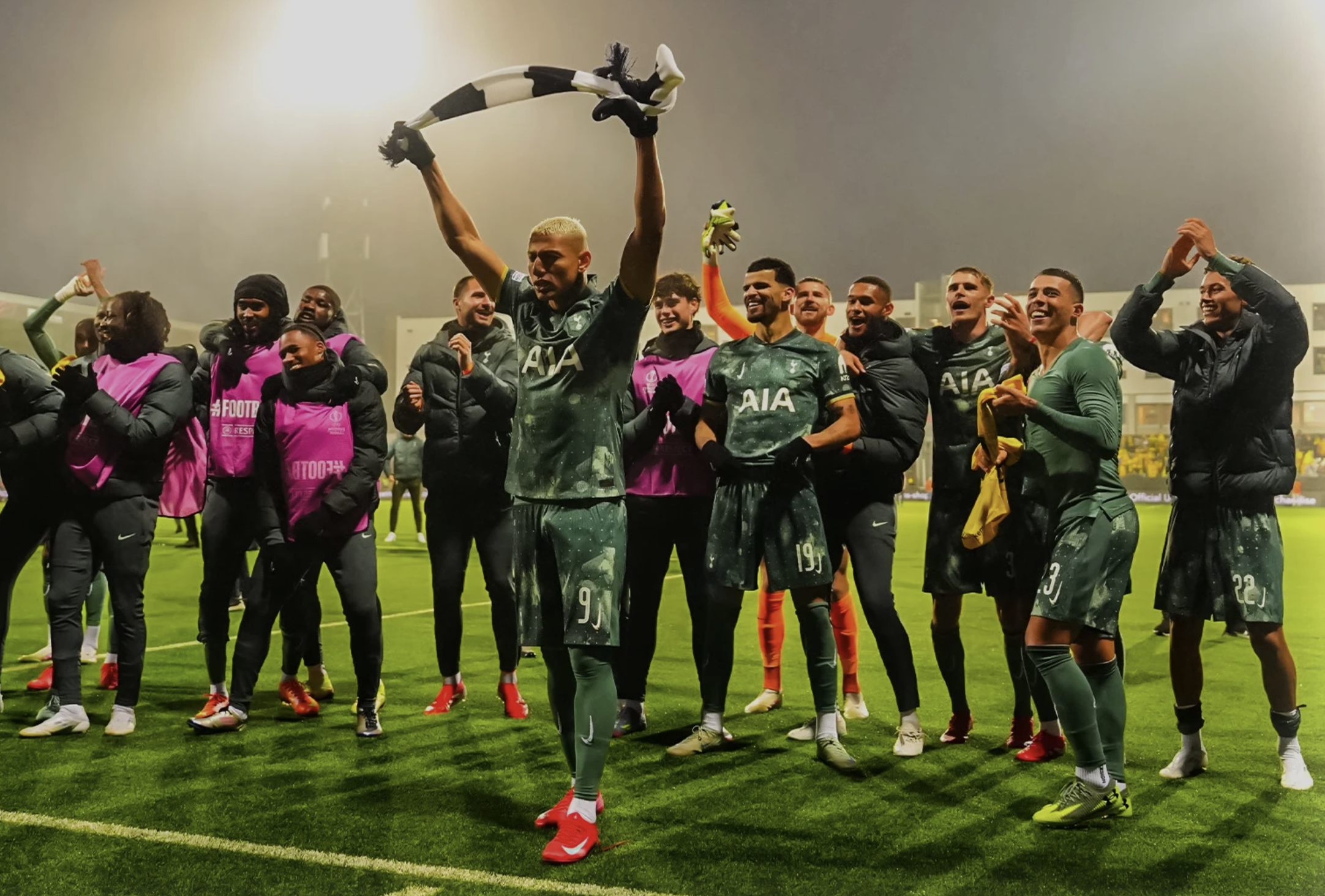 Richarlison holds up a scarf given to him by one of the traveling fans as he's flanked by teammates.