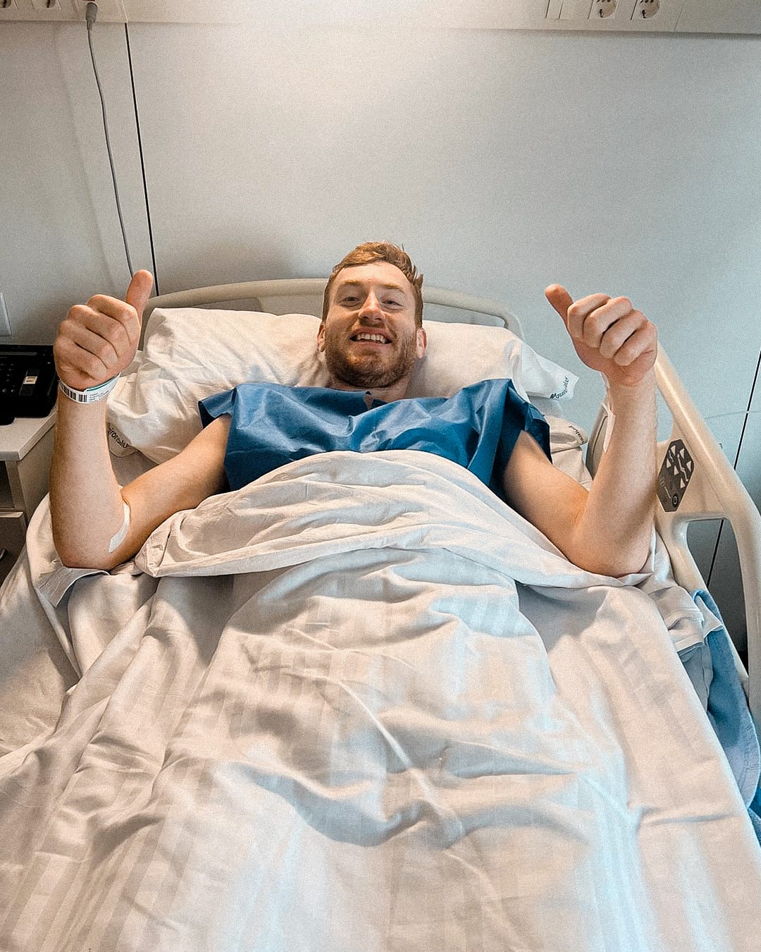 Dejan Kulusevski gives two thumbs up in a hospital bed while smiling.