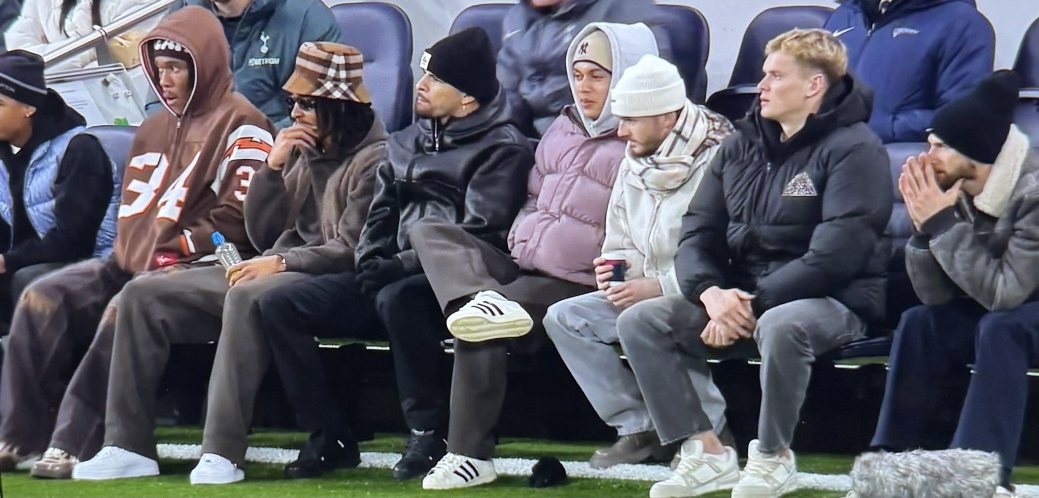 Several injured players sit on the sideline in their street clothes.