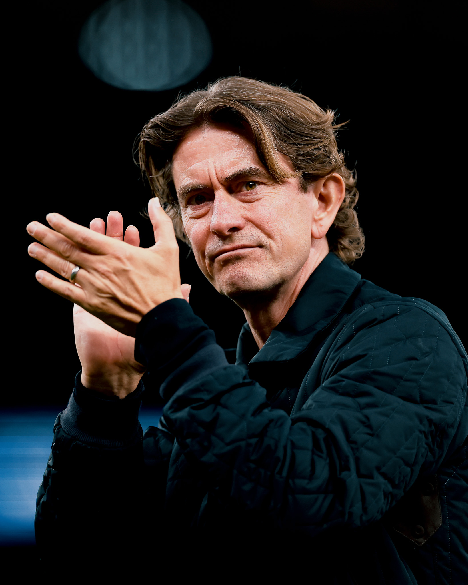 Thomas Frank claps in a quilted jacket.