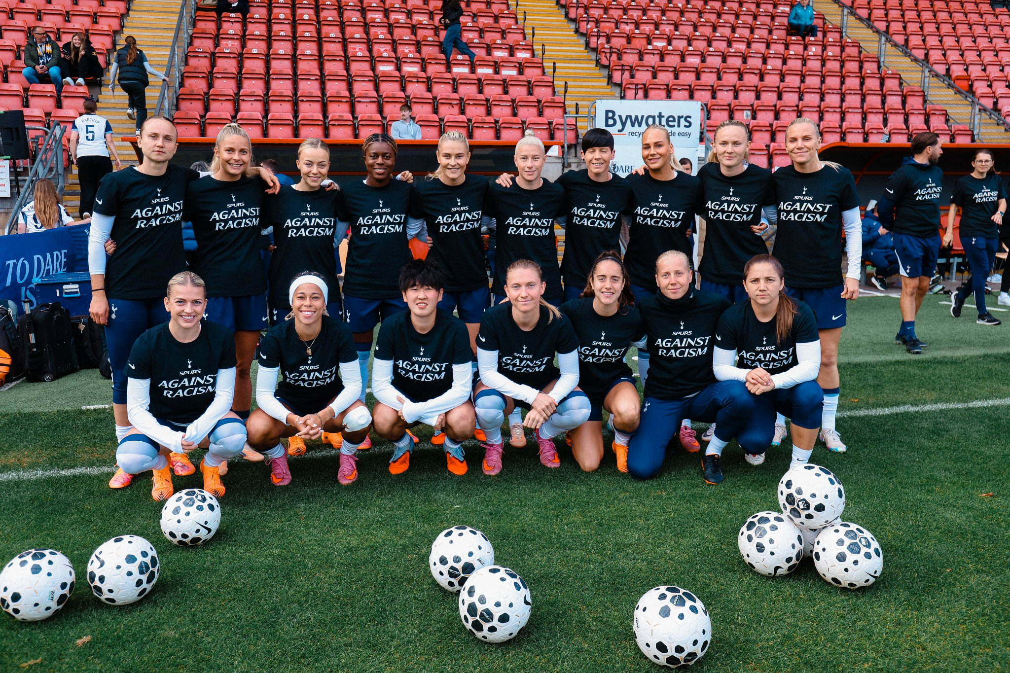 The starters and bench players pose together for a photo ahead of the game, all wearing shirts that say "Spurs against racism."
