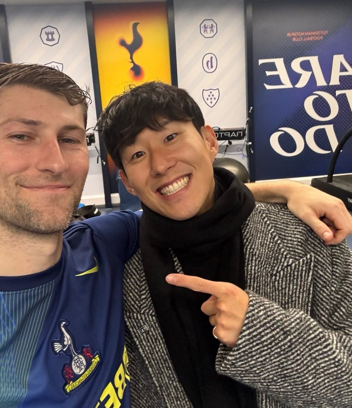 Ben Davies smiles close-mouthed and puts his arm around Son Heung-min, who is grinning toothily and pointing at his friend.