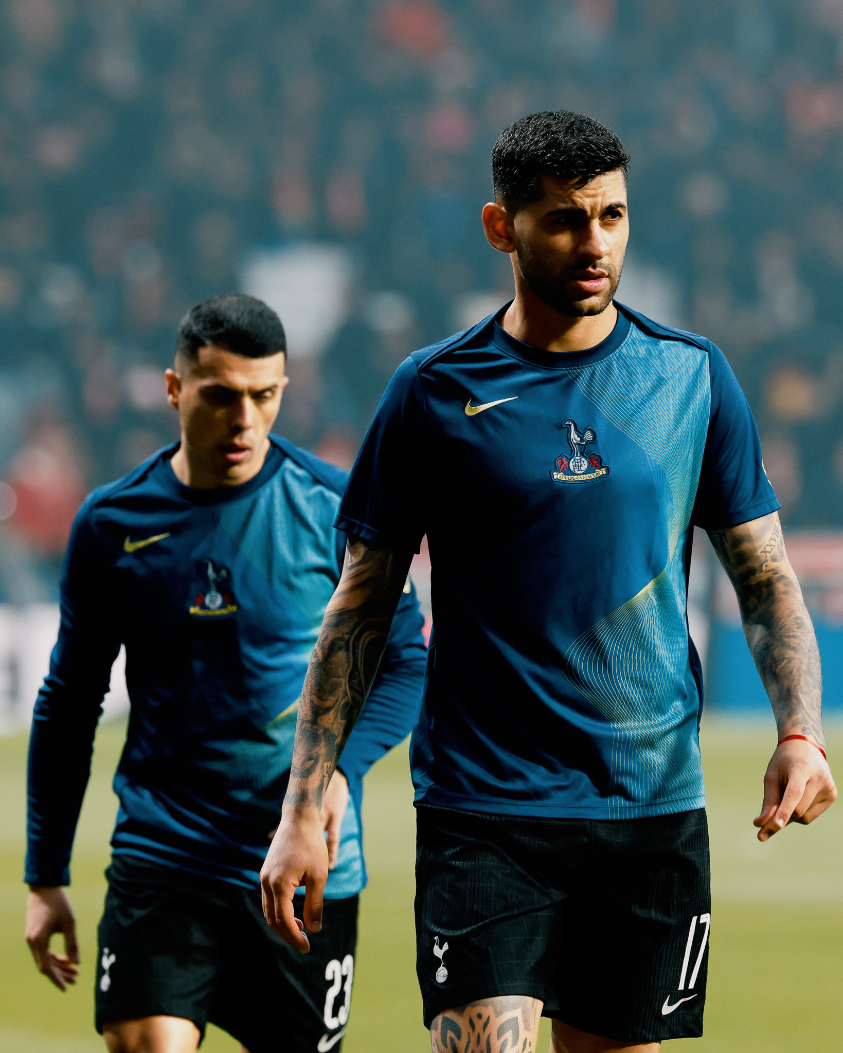 Cristian Romero walks half in shadow, with Pedro Porro behind him.