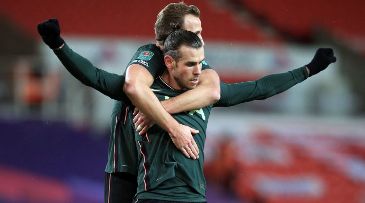 Harry Kane hugs Gareth Bale from behind and Bale stretches out his arms in triumph.