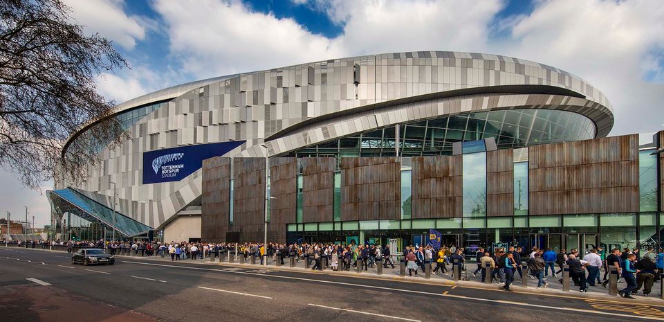 An exterior shot of Tottenham Hotspur Stadium, with fans walking in the foreground.