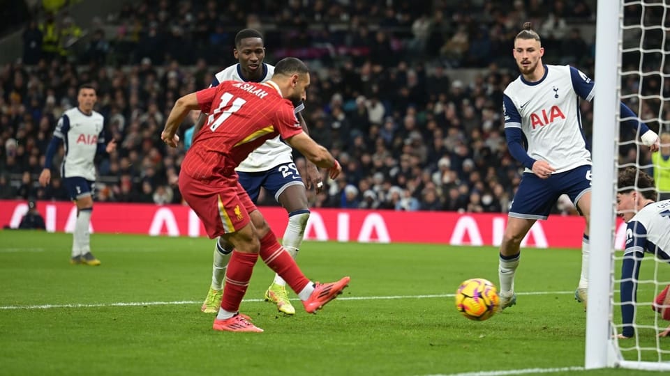 Mo Salah strikes the ball as Pape Sarr and Radu Drăgușin look on.