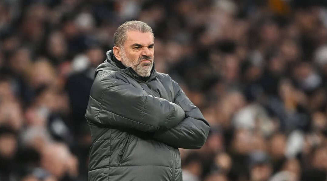 Ange Postecoglou grimaces on the sideline in his black puffer jacket. 