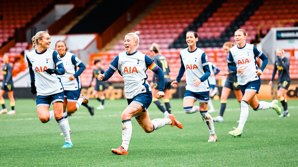 Beth England smiles and runs away to celebrate a goal, flanked by her teammates.