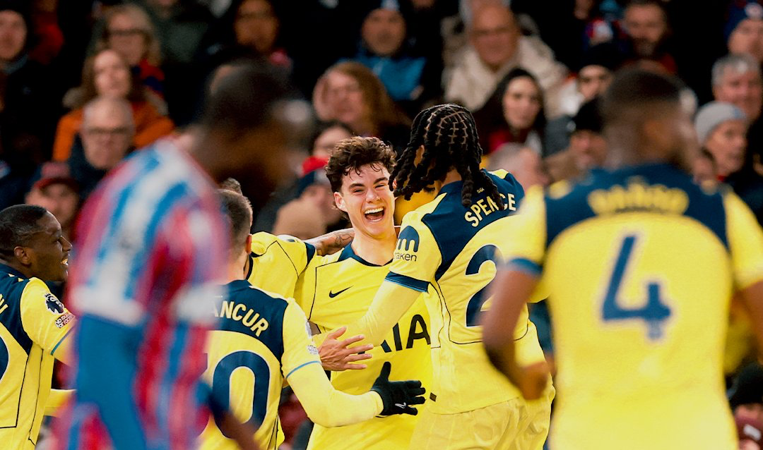 Archie Gray smiles as his teammates swarm him to celebrate his first Spurs goal.